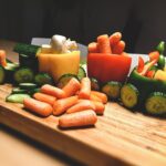 carottes et poivrons verts coupés en tranches sur une planche à découper en bois brun