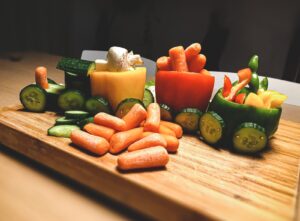 carottes et poivrons verts coupés en tranches sur une planche à découper en bois brun